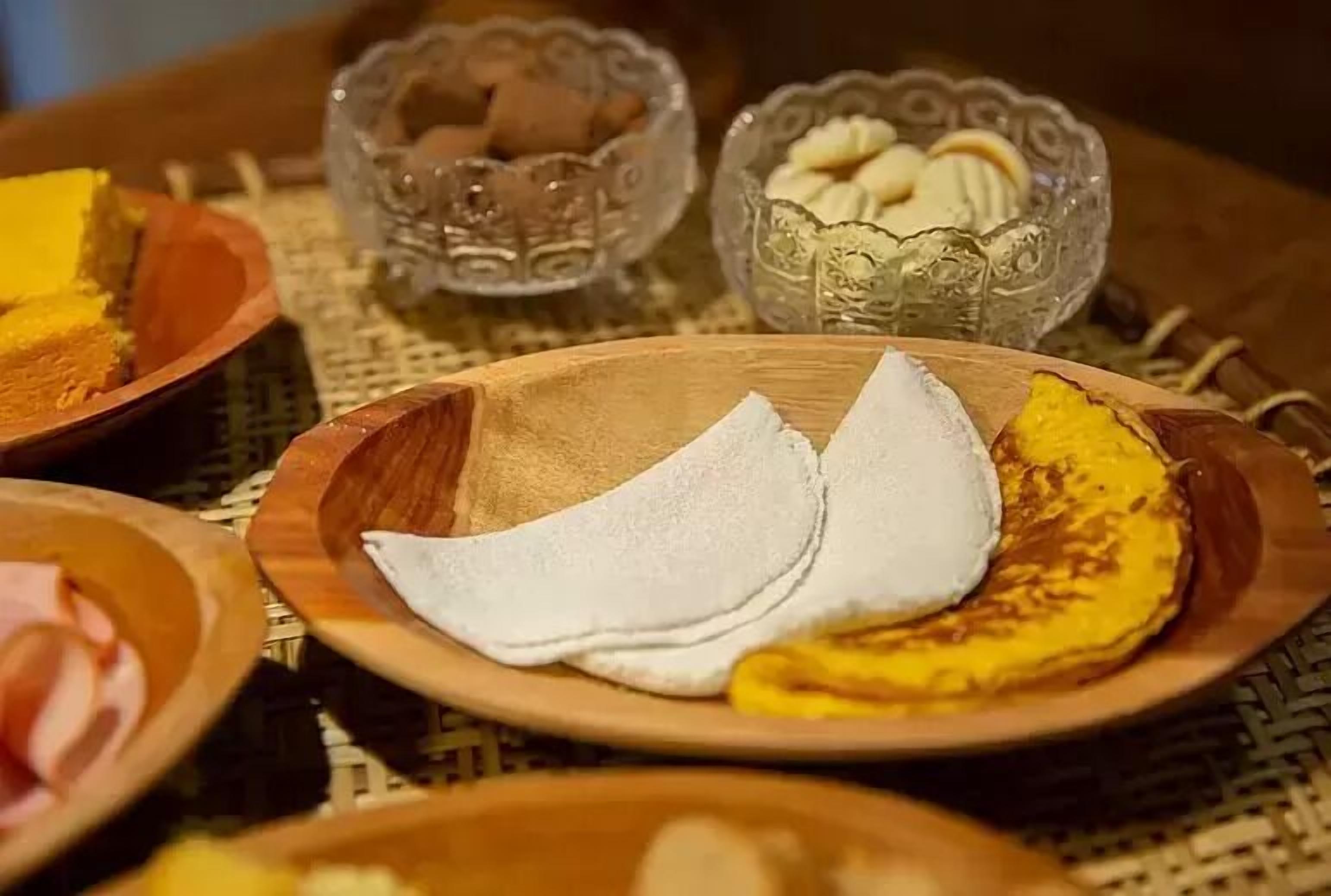 A wooden table with various food items, including a plate with banana slices and white bread.