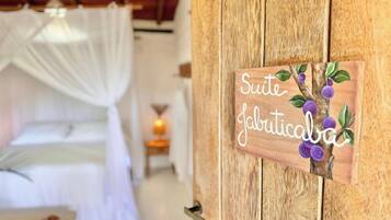 A wooden door with a sign that reads "Suite Jafriticaba" and a decorative branch with purple flowers.