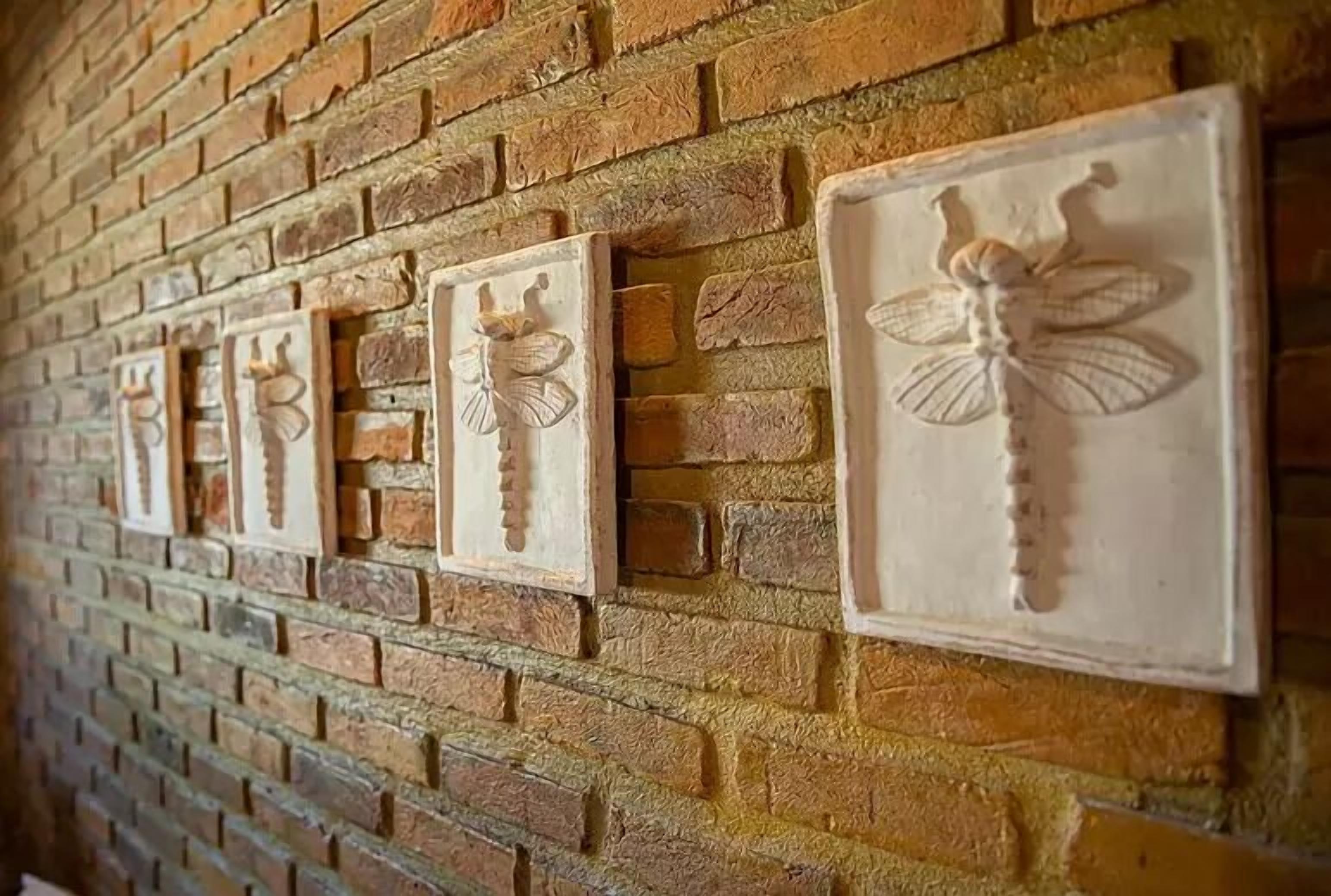 A brick wall with decorative plaques featuring dragonfly designs.