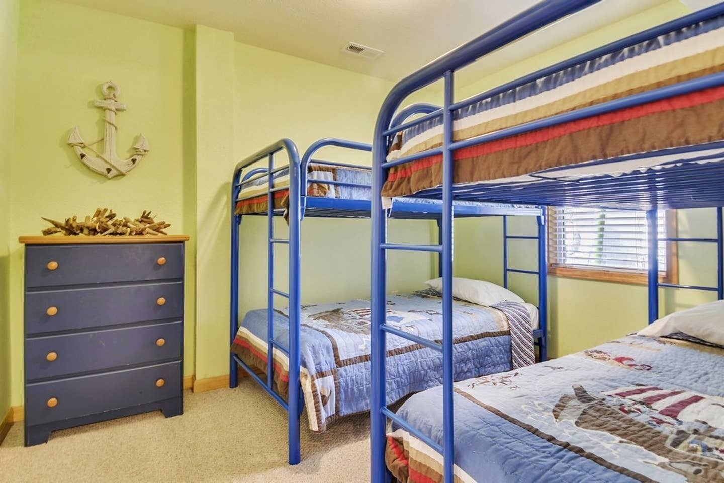 A room with bunk beds, a dresser, and a wall-mounted anchor decoration.
