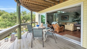 Un terrazzo in legno con mobili da esterno, vista sull'area living interna e un elemento d'acqua.
