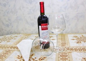A bottle of wine and an empty wine glass on a table with a lace tablecloth.