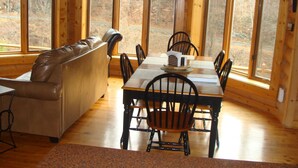 Un coin repas aménagé dans une cabane en bois, avec une table, des chaises et un canapé en cuir.
