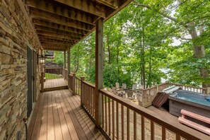 Relax on the deck surrounded by lush greenery, with a hot tub and outdoor seating area nearby.