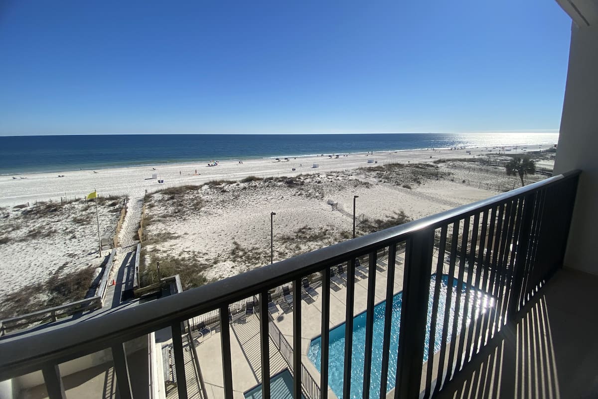 Ein Balkon mit Blick auf einen Strand und ein Schwimmbad.