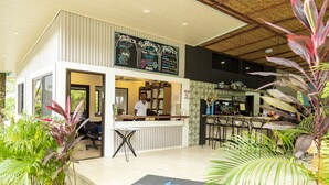 A modern bar area with a reception desk, seating, and a chalkboard menu. - Modern jungle full apartment in Teva Eco Retreat (Manuel Antonio)