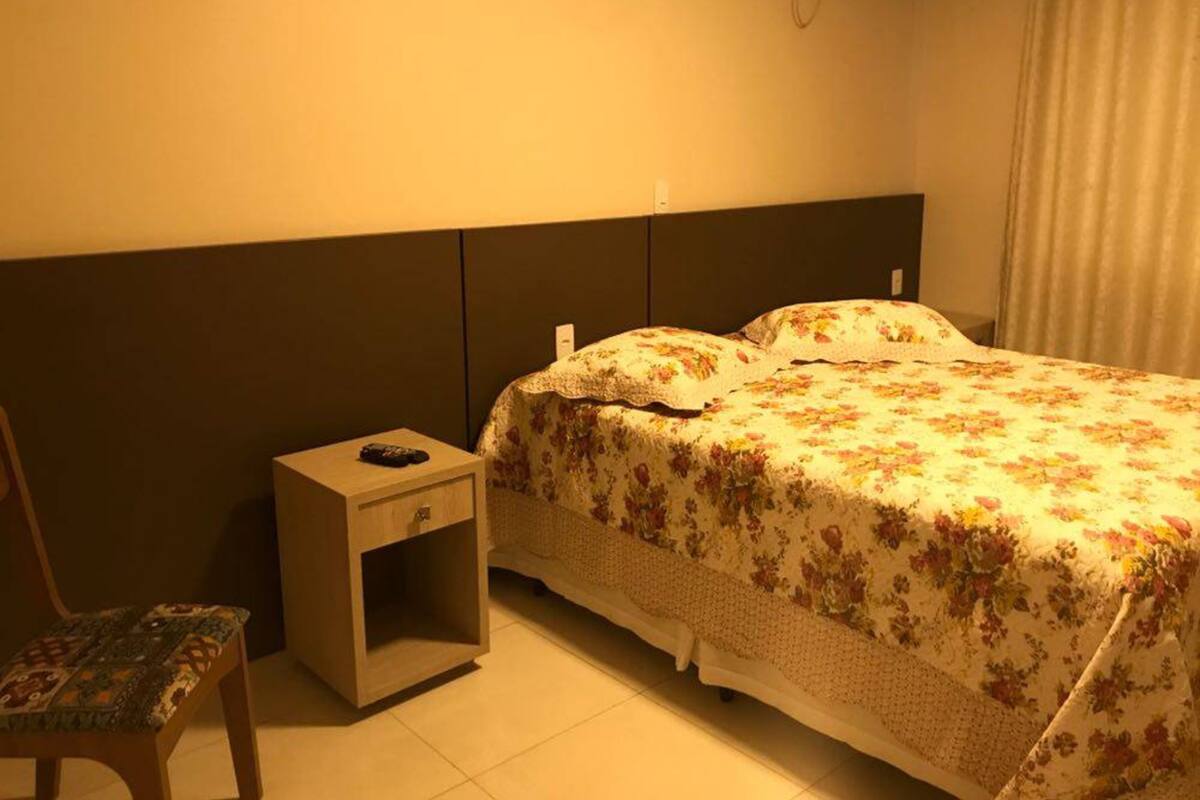 Una habitación de hotel con una cama, una mesita de noche y una silla.