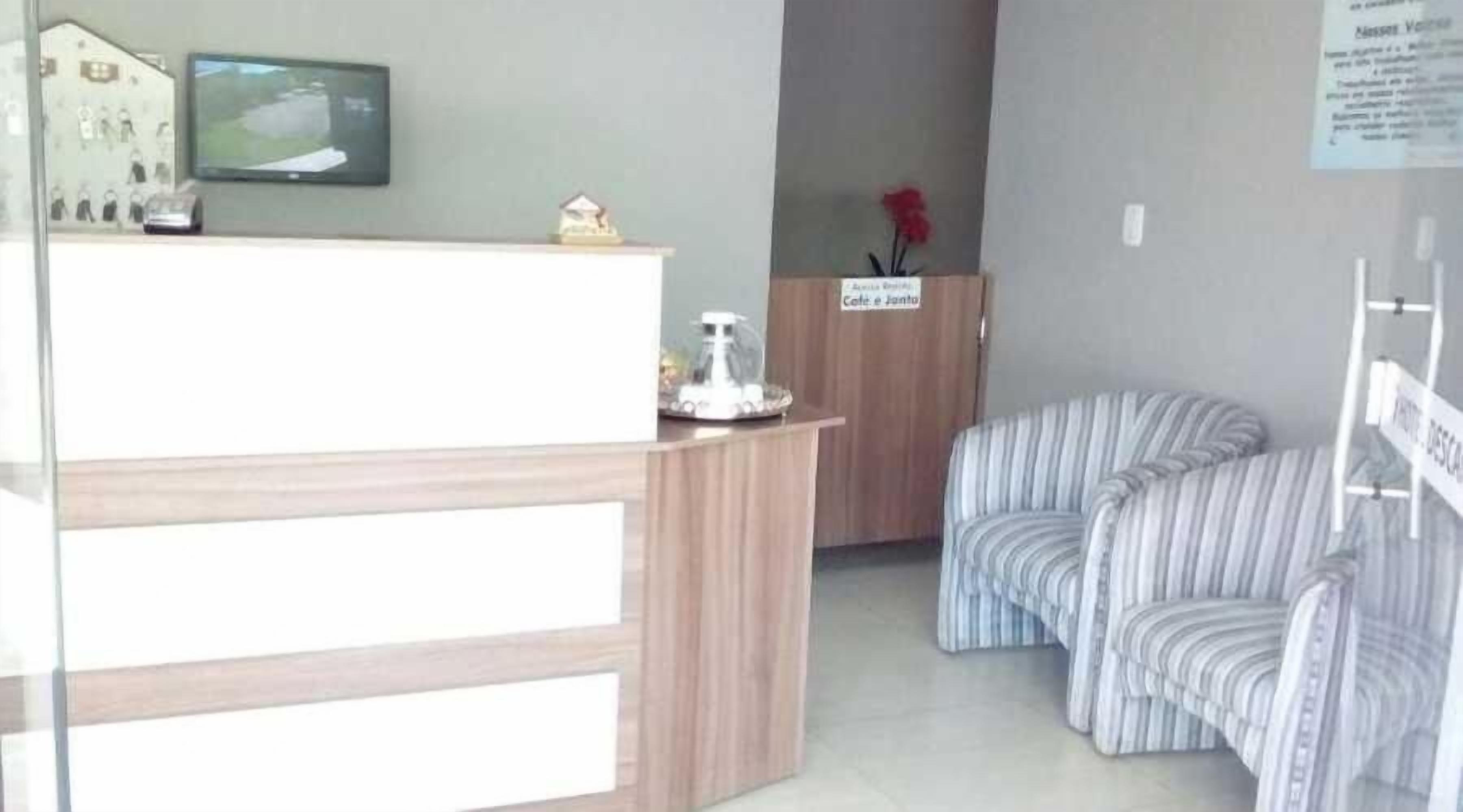 A reception area with a wooden desk, a television, and a sign indicating a waiting area.