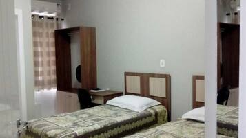 A hotel room with two single beds, a desk, and a wardrobe.