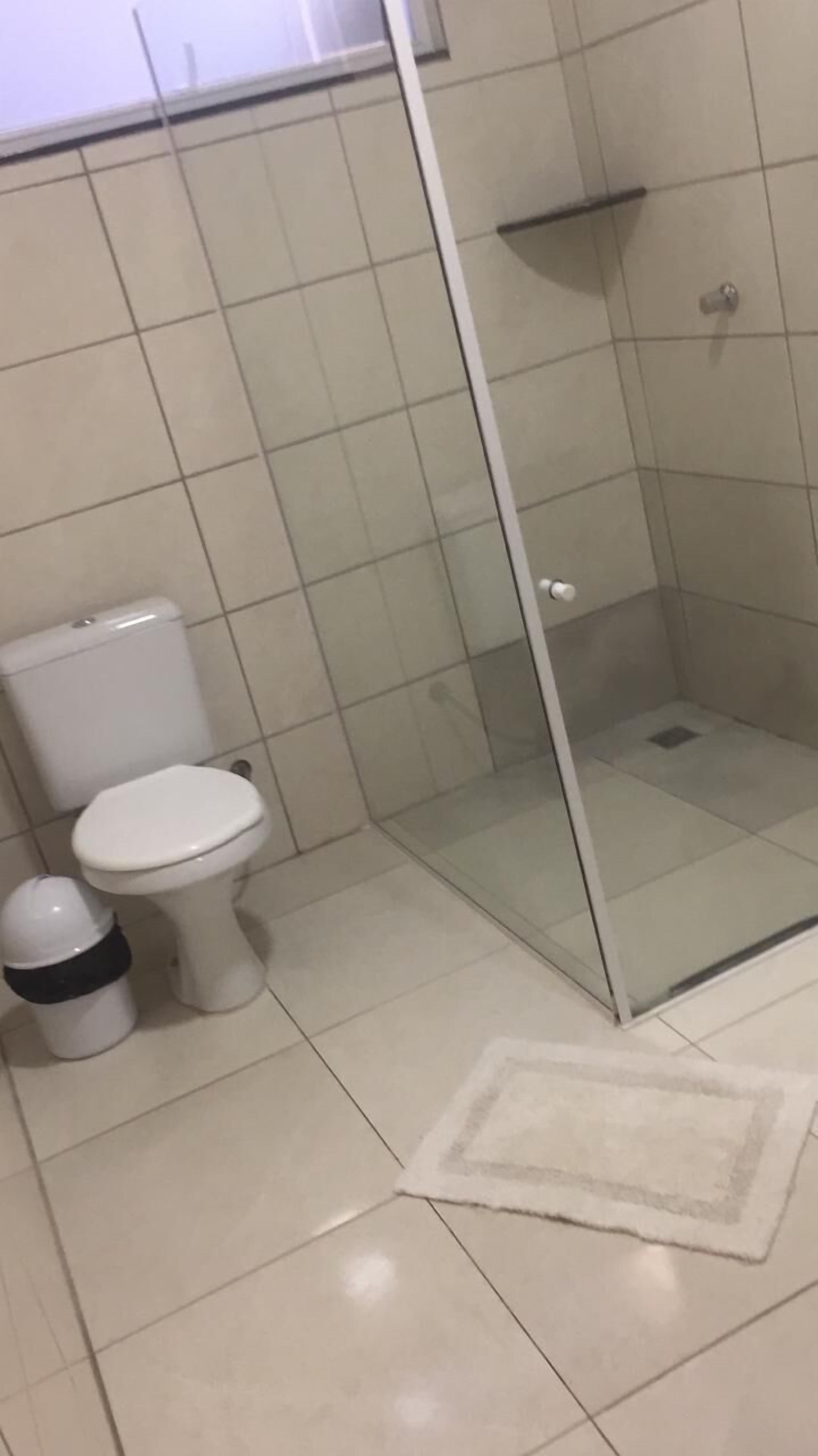 Un baño con inodoro, bidé y zona de ducha con mampara de vidrio.
