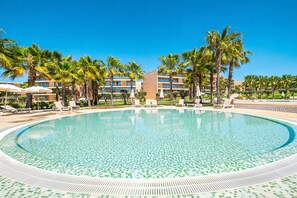 Une piscine avec des chaises longues et des palmiers.