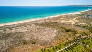 A coastal landscape with a beach, a paved walkway, and a road. - Comfortable apartment in an exclusive resort (Albufeira)