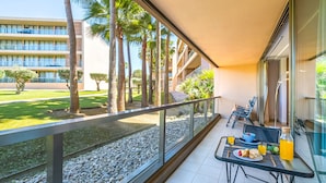 A balcony with a table set for breakfast, a view of a building, and a palm tree-lined pathway. - Comfortable apartment in an exclusive resort (Albufeira)