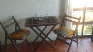 Un petit coin repas avec une table en bois et deux chaises, chacune agrémentée de coussins à motifs.