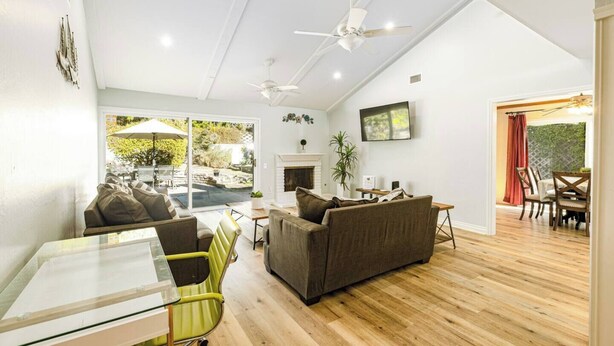 A modern living room with a glass table, green chair, brown sofa, and a fireplace.