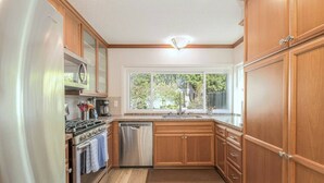 A kitchen with wooden cabinets, stainless steel appliances, and a window providing natural light.