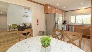 A modern kitchen with wooden cabinets, stainless steel appliances, and a dining area with a round table and chairs.