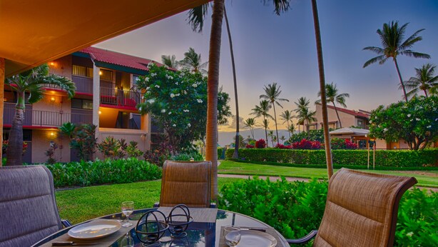 A dining area with a glass table, two chairs, and a plate with cutlery. - Gorgeous Ground Floor Oceanfront Condo, Just Steps Away From Pool & Beach! (Kihei)