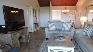 A living room with a television, sofas, a coffee table, and a wooden cabinet. - BT 3843 Ocean View Condo-Paradise Vacation Rental in Ocean Village (Fort Pierce)