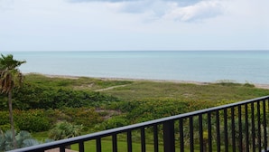 A balcony with a view of the sea and a grassy area with plants. - SS 4152 Ocean View Condo- in Ocean Village (Fort Pierce)