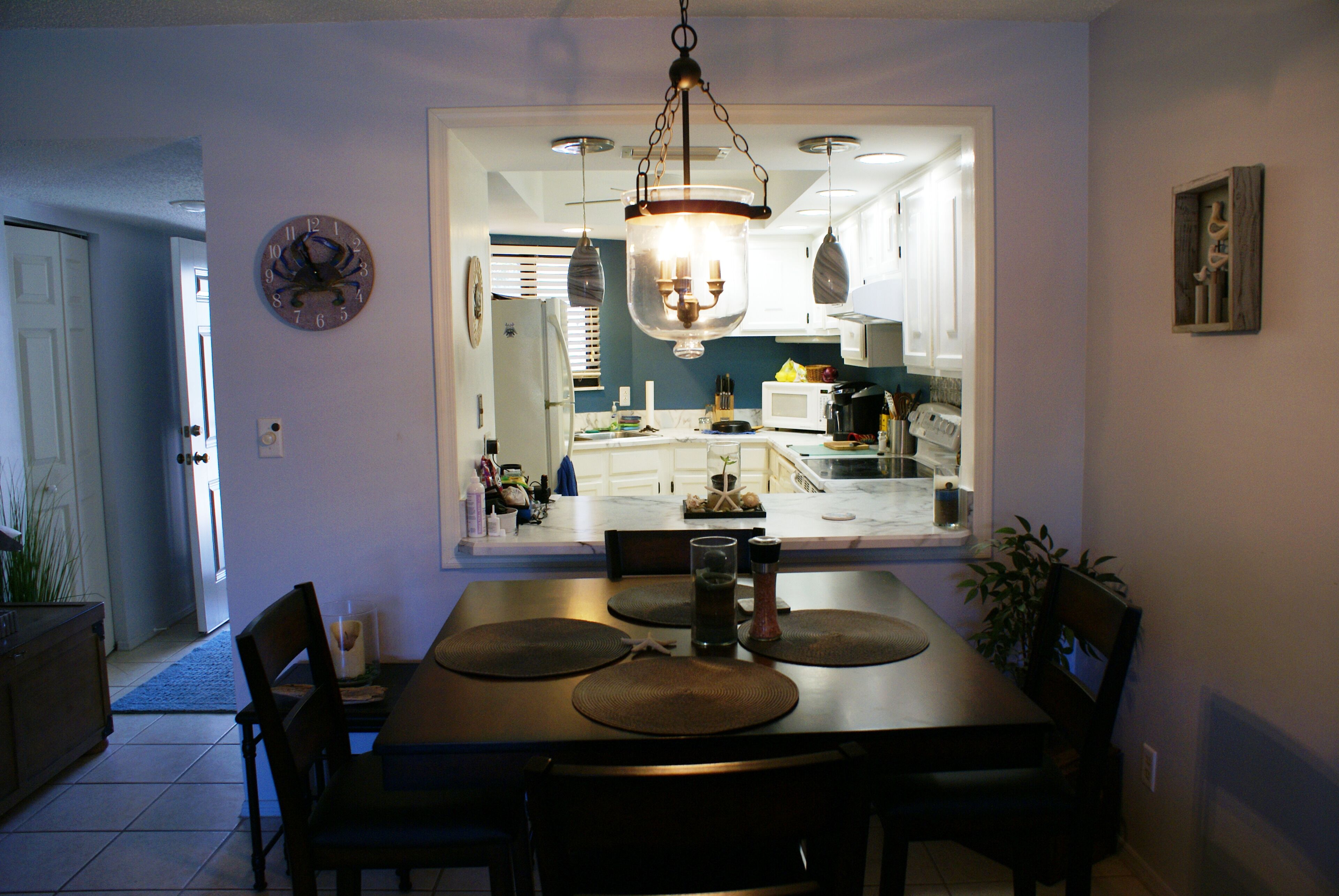 A dining area with a table, chairs, and a hanging light fixture.