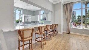 A modern kitchen with white cabinets, a central island, and bar stools. - BT 3313 Fountain View Condo w/Deck-Paradise Vacation Rental in Ocean Village (Fort Pierce)