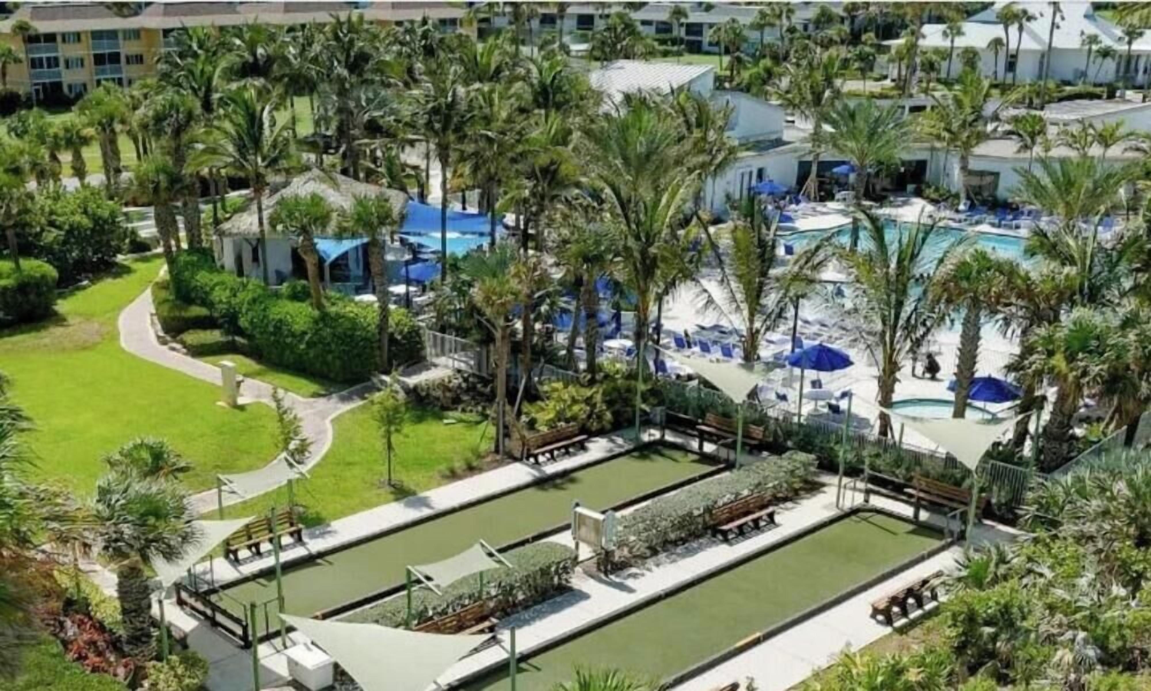 A resort with multiple swimming pools, palm trees, and lounge areas.