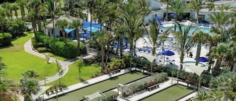 A resort with multiple swimming pools, palm trees, and lounge areas.
