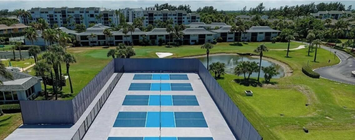 Un hotel moderno con area piscina sul tetto, circondato da vegetazione lussureggiante e un campo da golf.
