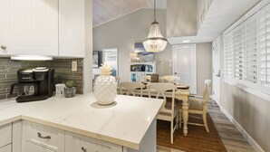 A kitchen with a white marble countertop, a coffee maker, and a decorative pineapple vase. - CP 133 Ocean Front Condo - Vacation Rental in Ocean Village (Fort Pierce)