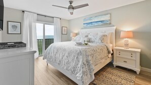 A bedroom with a bed, nightstands, a ceiling fan, and a view of the outdoors. - CP 133 Ocean Front Condo - Vacation Rental in Ocean Village (Fort Pierce)