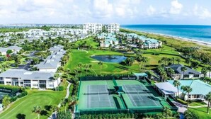 A golf course with a tennis court, surrounded by residential buildings and a beach. - CP 822 Golf Course View Condo - Paradise Vacation Rental in Ocean Village (Fort Pierce)