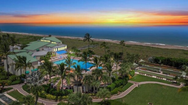 A resort with a large pool, palm trees, and a view of the ocean at sunset. - CP 822 Golf Course View Condo - Paradise Vacation Rental in Ocean Village (Fort Pierce)
