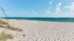 A sandy beach with clear blue water and a few clouds in the sky. - CP 822 Golf Course View Condo - Paradise Vacation Rental in Ocean Village (Fort Pierce)