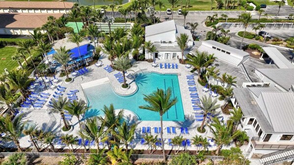 Relax by the resort pool surrounded by palm trees and lounge chairs.