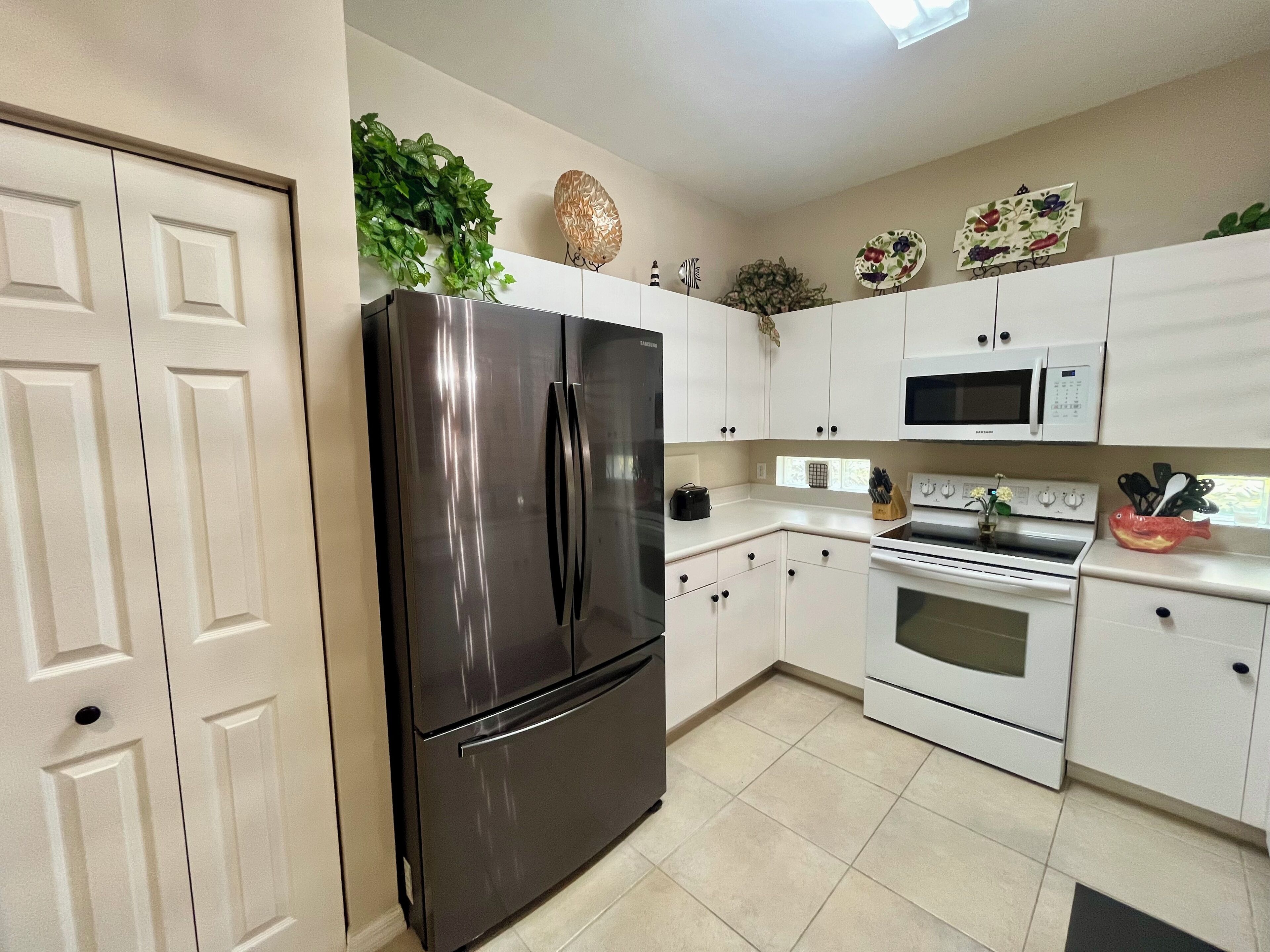 A modern kitchen with white cabinets, stainless steel appliances, and decorative items.