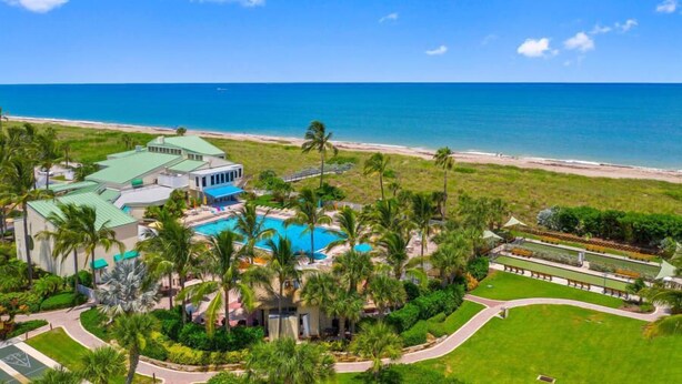 A resort with a swimming pool, palm trees, and a beach view. - CT 2345- Ocean View Condo  -  in Ocean Village (Fort Pierce)