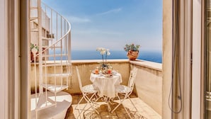 A balcony with a white table set for two, surrounded by white chairs, and a white spiral staircase. - VILLA COSTIERA - Five Bedroom Villa, Sleeps 10 (Amalfi)