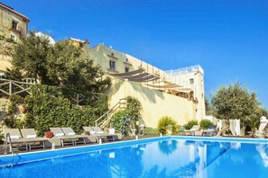 A swimming pool with lounge chairs and a building with a balcony in the background. - VILLA COSTIERA - Five Bedroom Villa, Sleeps 10 (Amalfi)