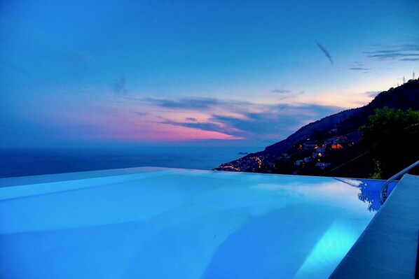 A large infinity pool with a view of a coastal town at sunset. - VILLA COSTIERA - Five Bedroom Villa, Sleeps 10 (Amalfi)