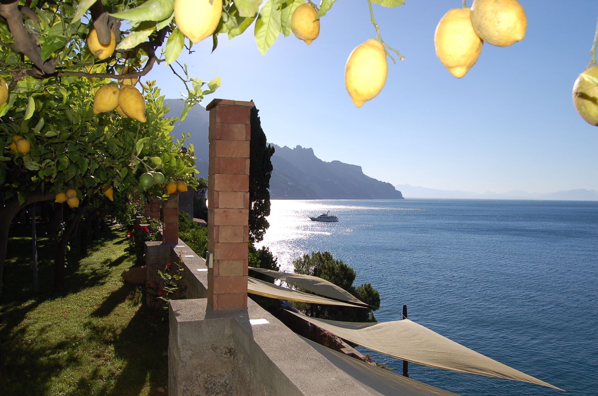 Vista sulla costa con mare, una barca e un edificio con una colonna in mattoni.