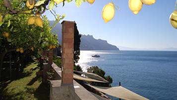 Vista sulla costa con mare, una barca e un edificio con una colonna in mattoni.