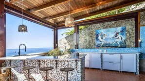 A kitchen with a large island, bar stools, a sink, and a view of the sea. - SELENE - Eight Bedroom Villa, Sleeps 16 (Ravello)