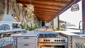 An outdoor kitchen with a stone wall, a built-in oven, and a gas stove. - SELENE - Eight Bedroom Villa, Sleeps 16 (Ravello)