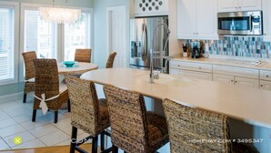 A modern kitchen with white cabinets, a stainless steel refrigerator, and a built-in microwave. - Oceanfront 9 bdrms with pool and hot tub (Carolina Beach)