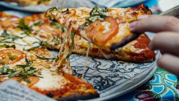 A pizza with visible toppings and cheese, served on a patterned plate.