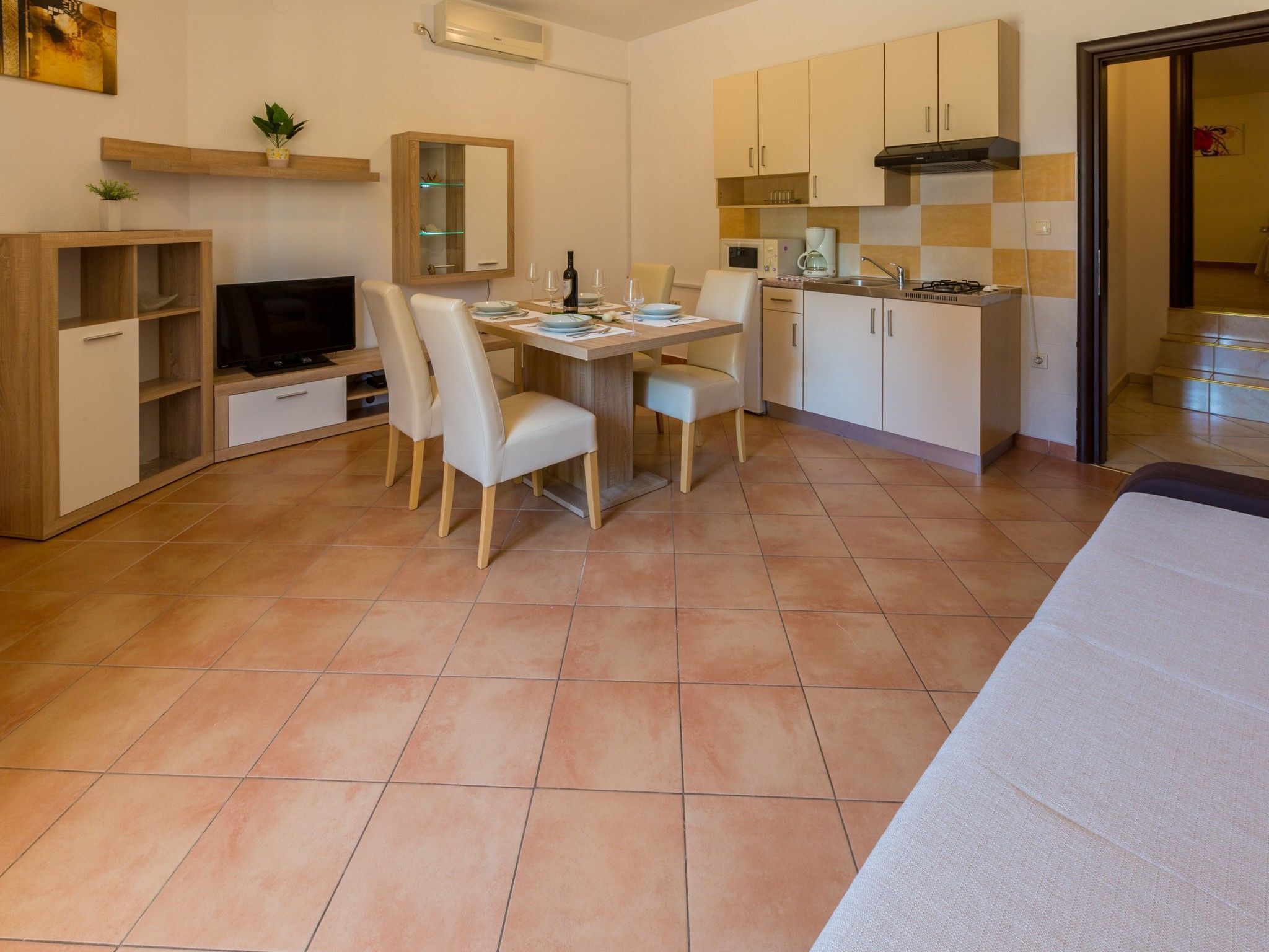 A compact living space with a dining area, kitchenette, and a TV.