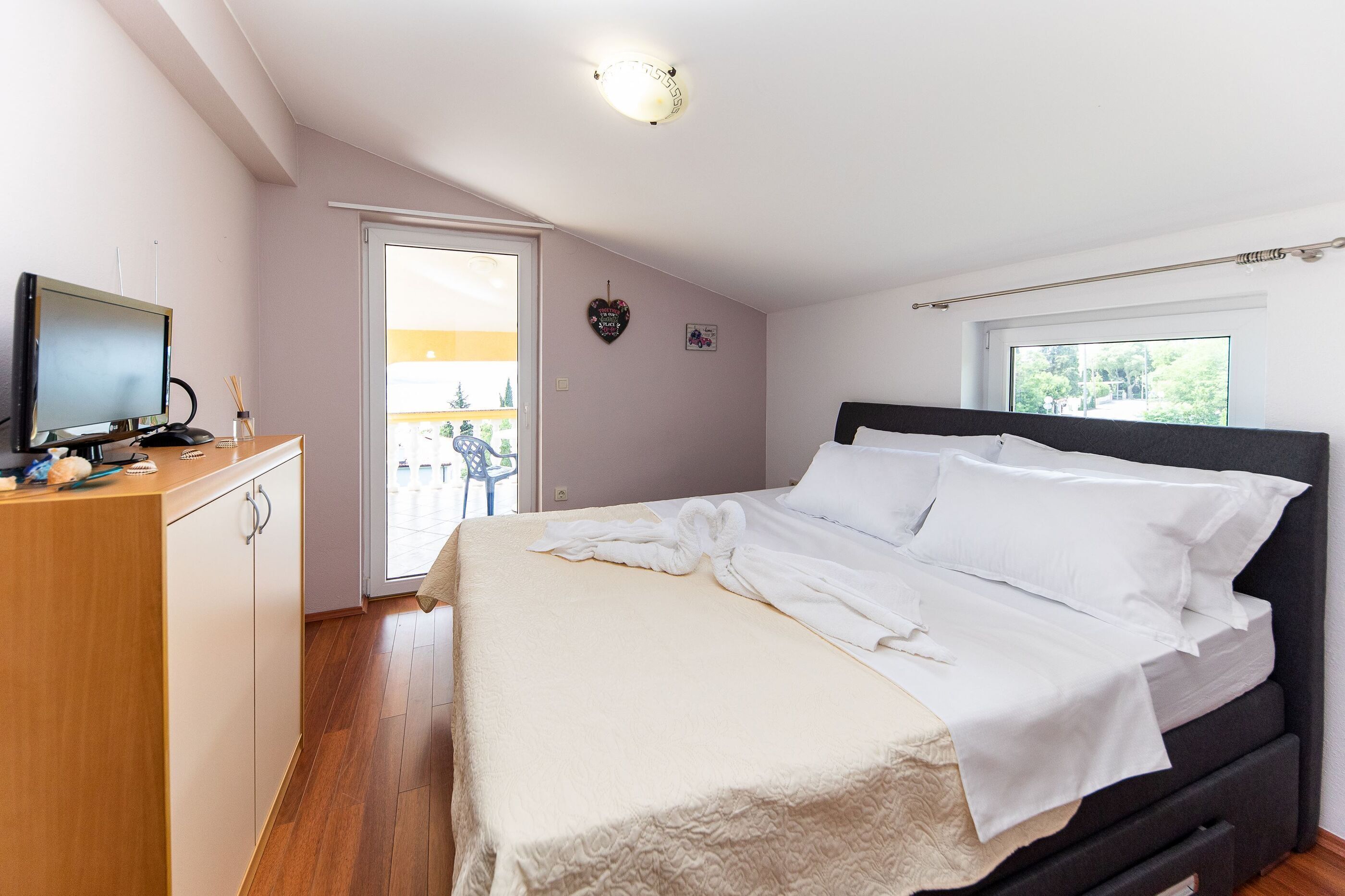 A bedroom with a bed, a desk, and a television.