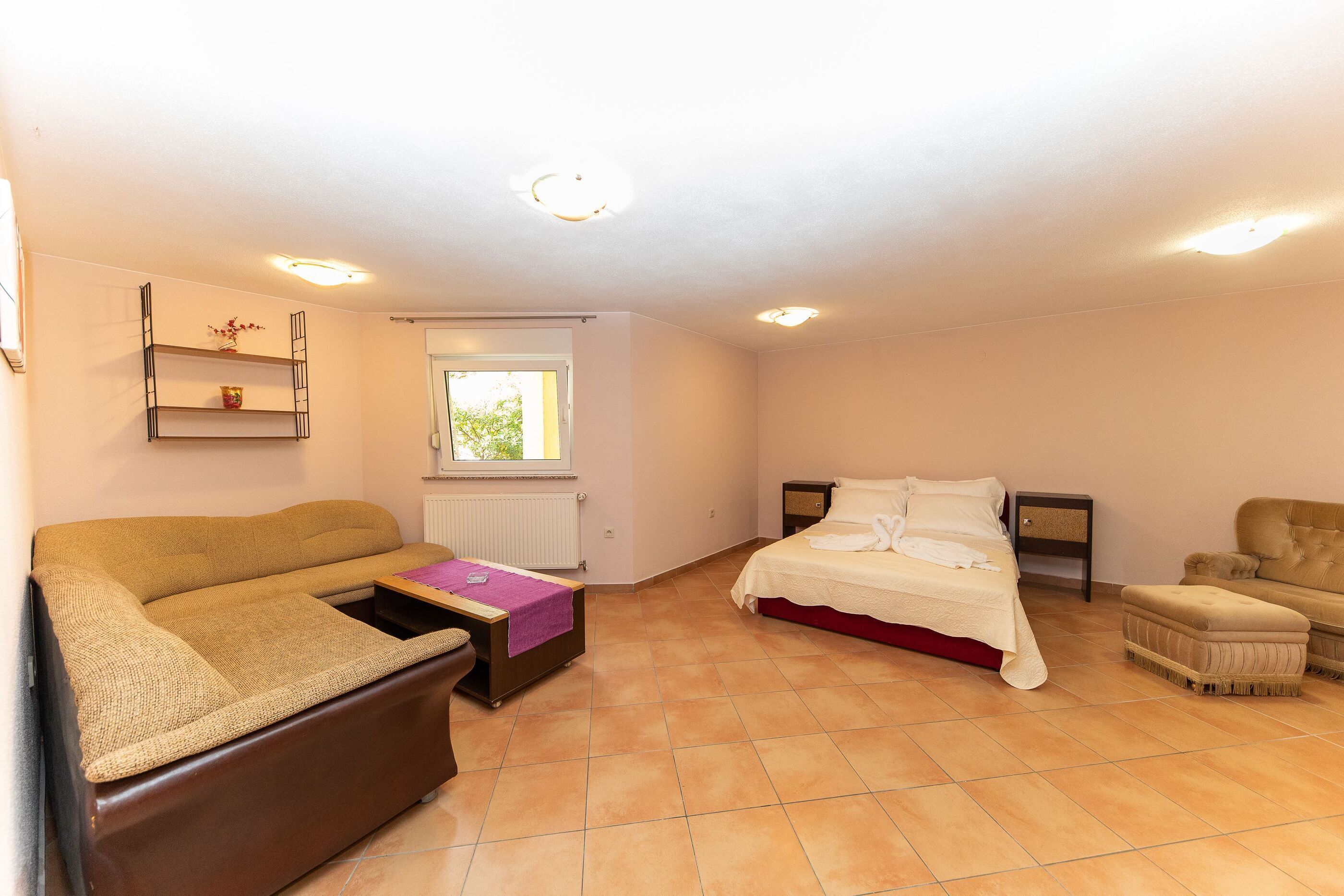 A bedroom with a bed, a sofa, a chair, and a small table.