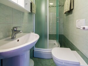 A bathroom with a sink, toilet, and glass-enclosed shower.